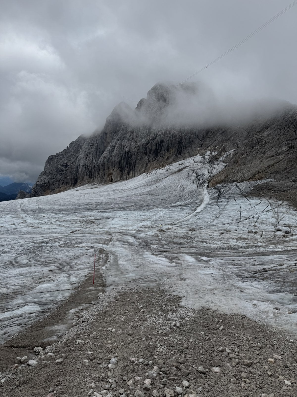 Der Dachstein-Gletscher mit Geröllfeld und Schmelzwasser unter Wolken auf über 2700 Metern