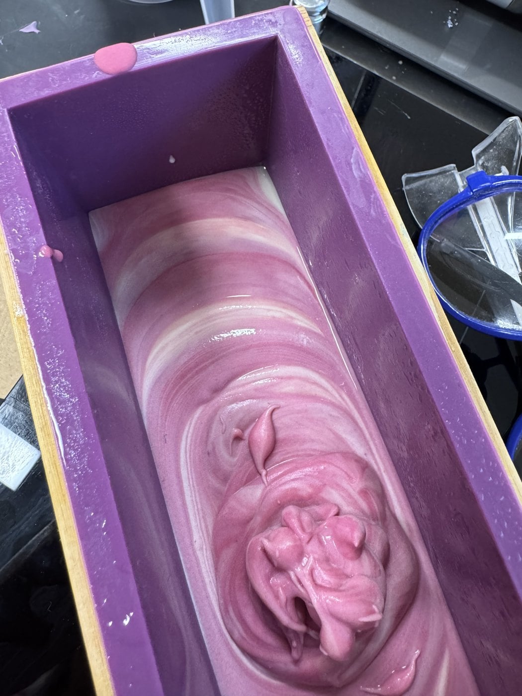 Frisch gegossene, rosa marmorierte Seife in einer Silikonform mit Holzrahmen – handgesiedete Naturseife nach dem Live-Sieden